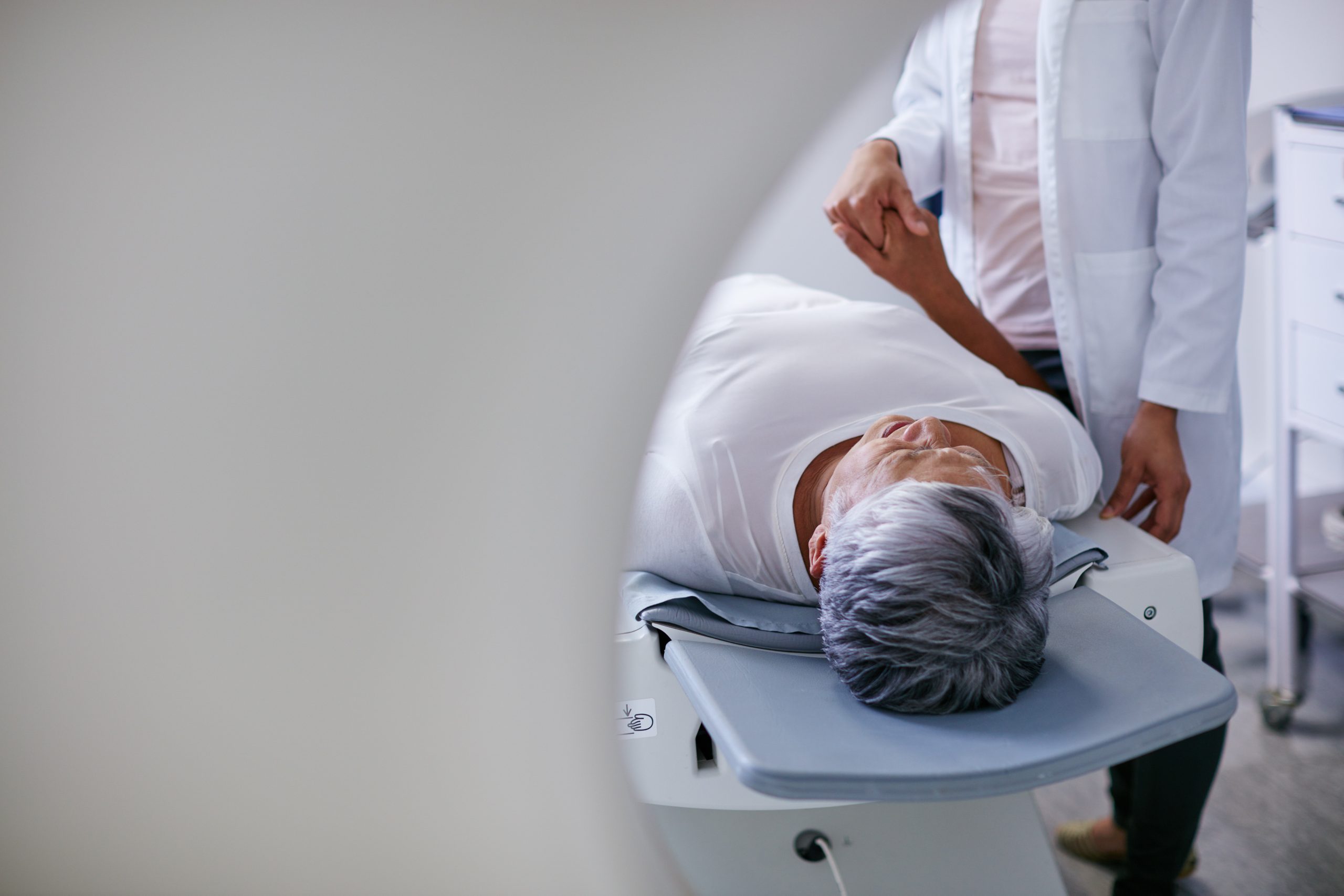Doctor, mri and woman holding hands of patient in hospital before scanning in machine. Ct scan, cancer and medical professional with senior person in radiology test for healthcare in clinic.